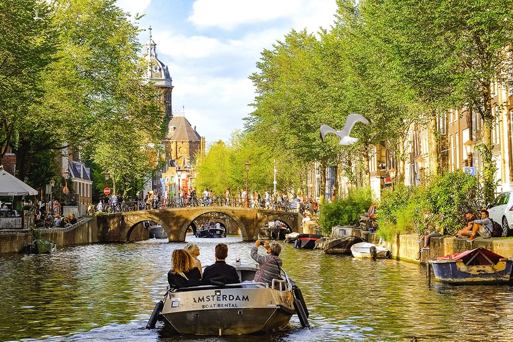 Amsterdam canal with gabled houses and houseboats at golden hour
