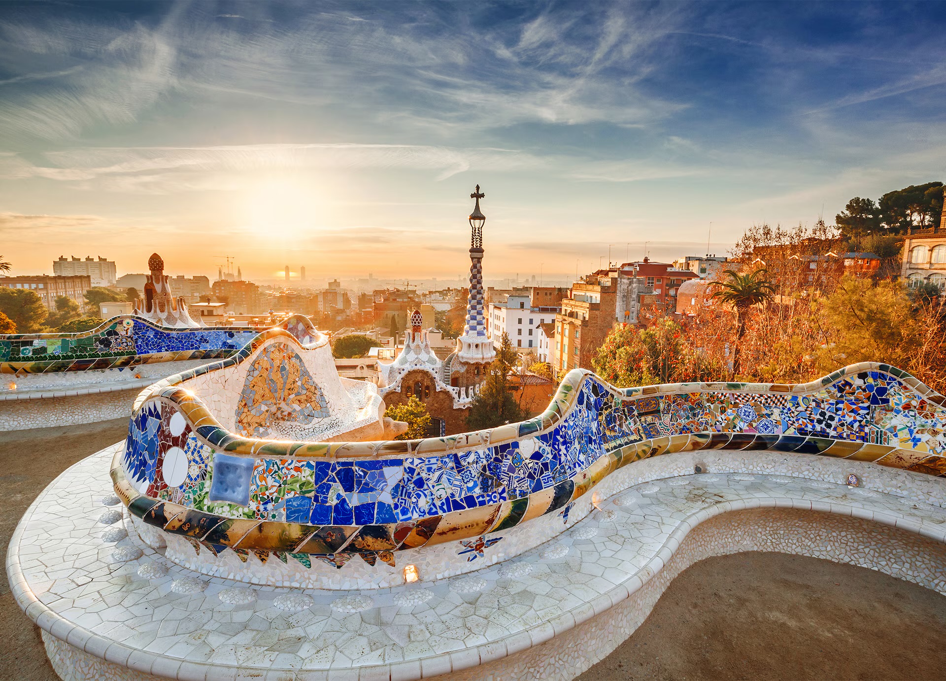 Casa Batlló's colourful Modernista facade on Passeig de Gràcia at golden hour, with palm trees lining the boulevard